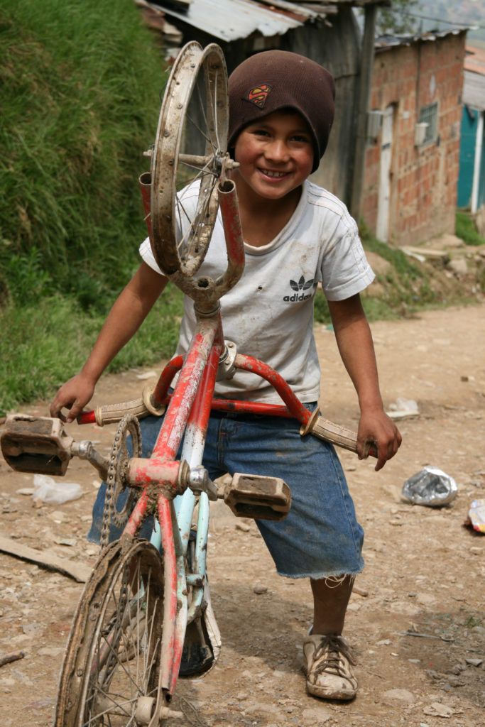 En 8-årig pojke poserar med sin cykel i området Corinto barrio, Colombia.