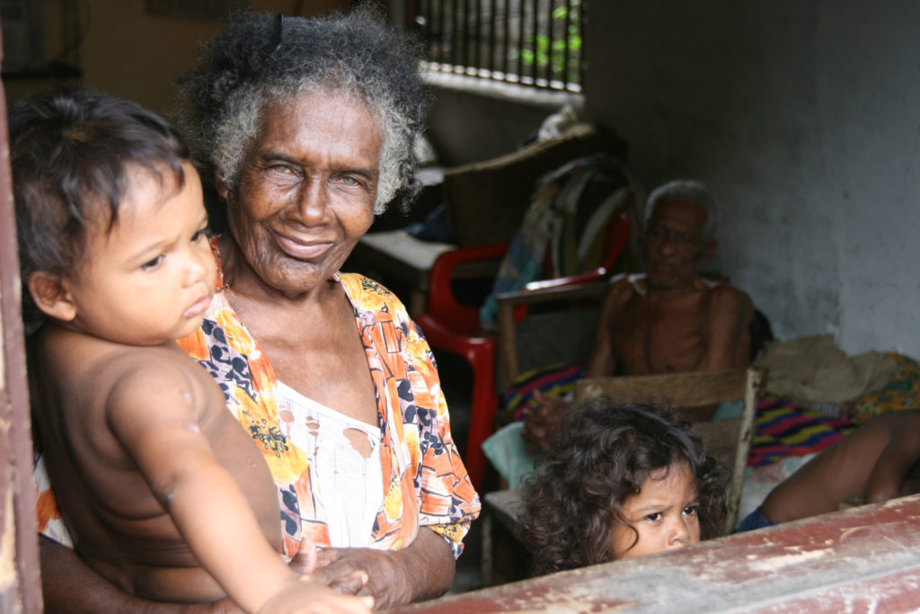 Bild på en leende äldre kvinna med två barn.